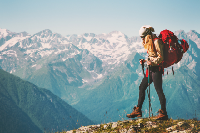 "An adventurous woman stands triumphantly on a mountain peak, surrounded by breathtaking views. Adventure Captions for Instagram."